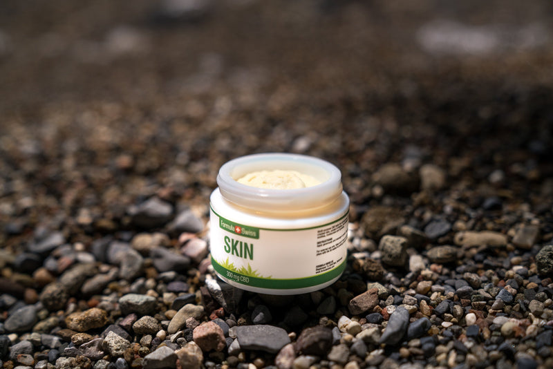 Open pot Formula Swiss CBD Skin-balsem, 300 mg CBD, op een kiezelstrand
