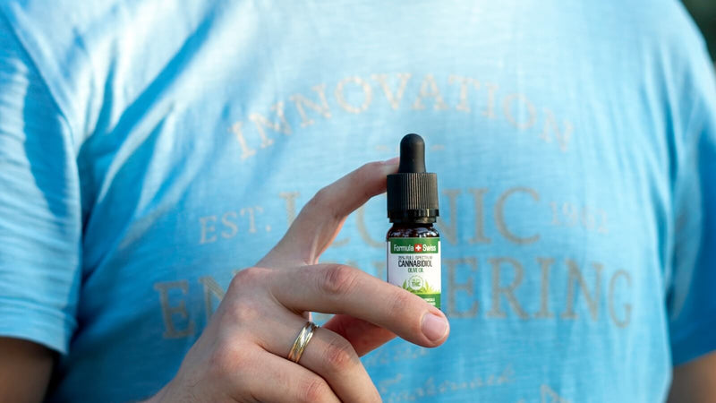 Een hand met een flesje van 10 ml CBD-olie van Formula Swiss in olijfolie