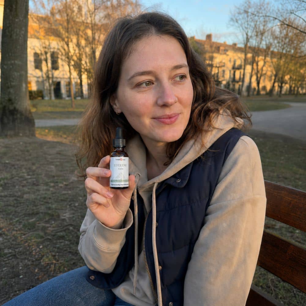 Vrouw met een flesje Lucerne CBD-olie buiten in een park