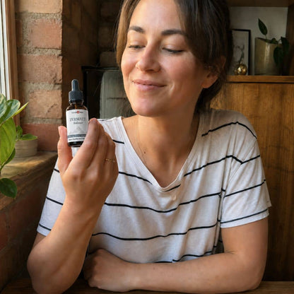Vrouw met een flesje Zermatt CBD-olie in een gezellig interieur.